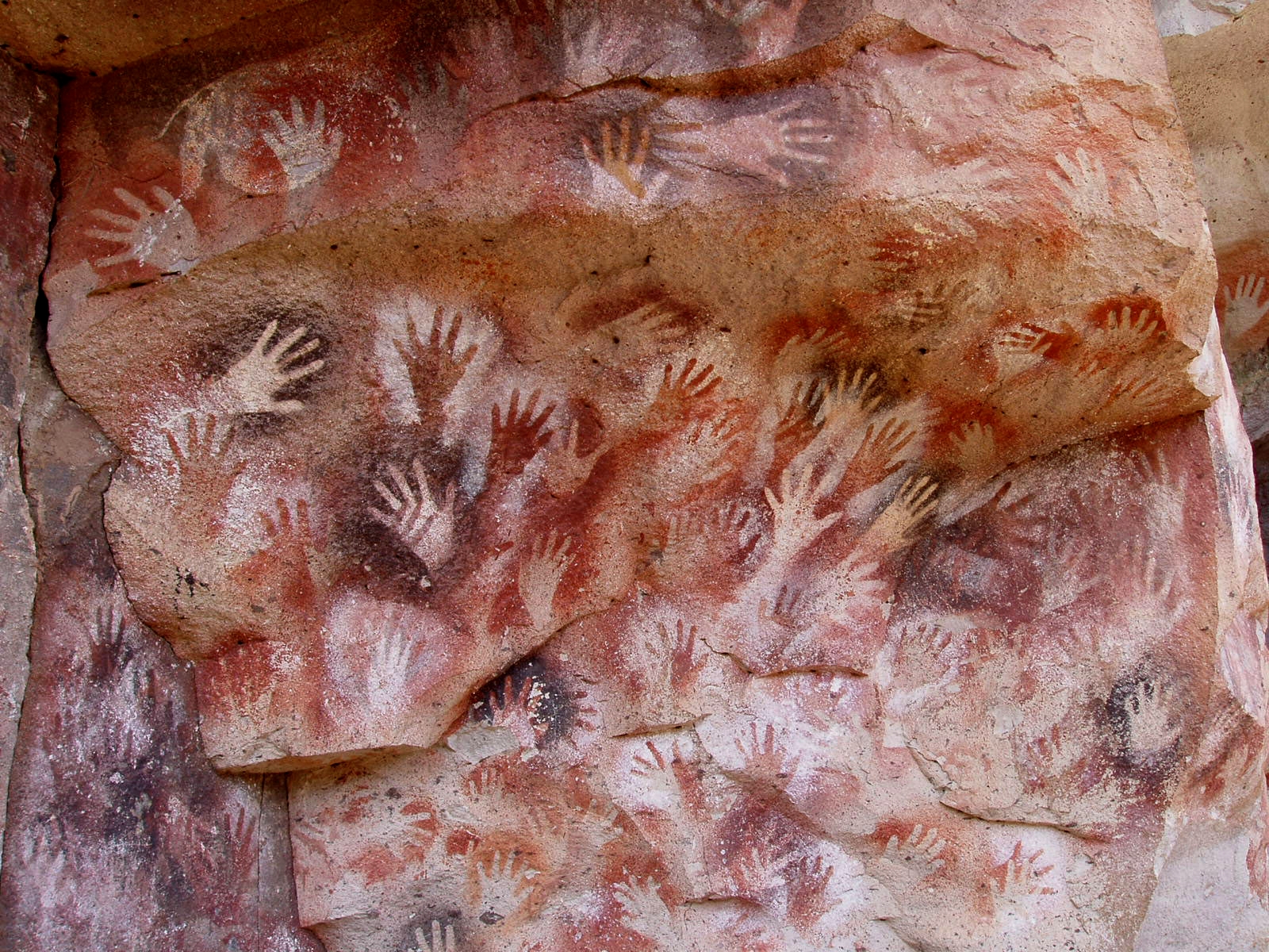 The Cueva de las Manos in Santa Cruz, Argentina, its rock wall covered in hundreds of stencilled human hands in ochre and manganese.