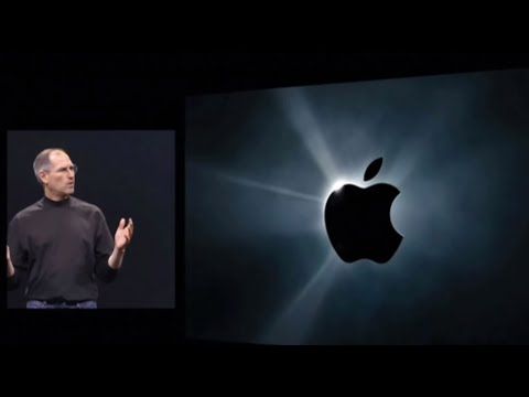 Steve Jobs on stage during the 2007 keynote, a glowing Apple logo filling the screen behind him.